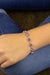 Bracelet with purple gemstones on a wrist, wearing blue jeans.