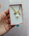 Hand holding a gold curb chain necklace with celestial charms, including an amethyst star, a pearl sun, and a labradorite moon, packaged by Jill Makes, titled 'Pearl and Moon Celestial Charm Necklace'.
