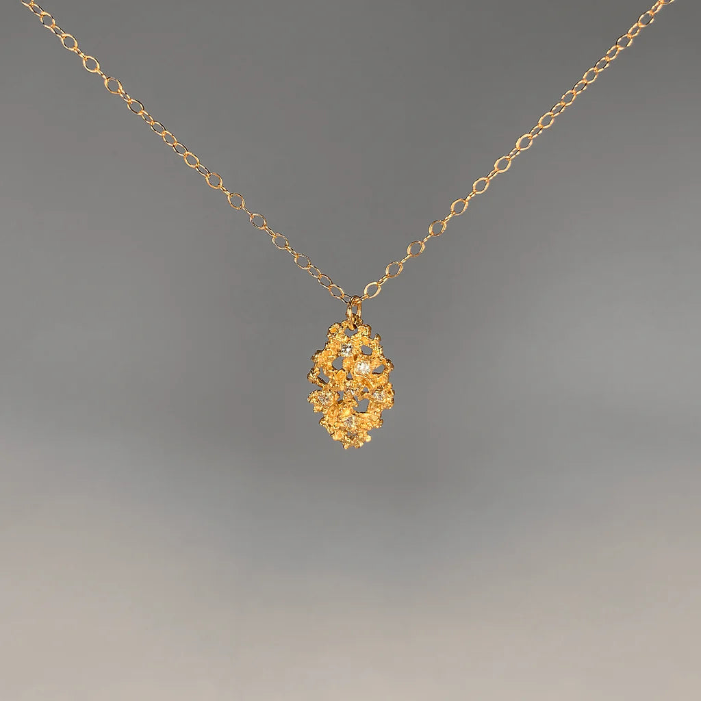 Gold necklace with a decorative gold leaf pendant with gemstone