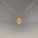 Gold necklace with a decorative gold leaf pendant with gemstone