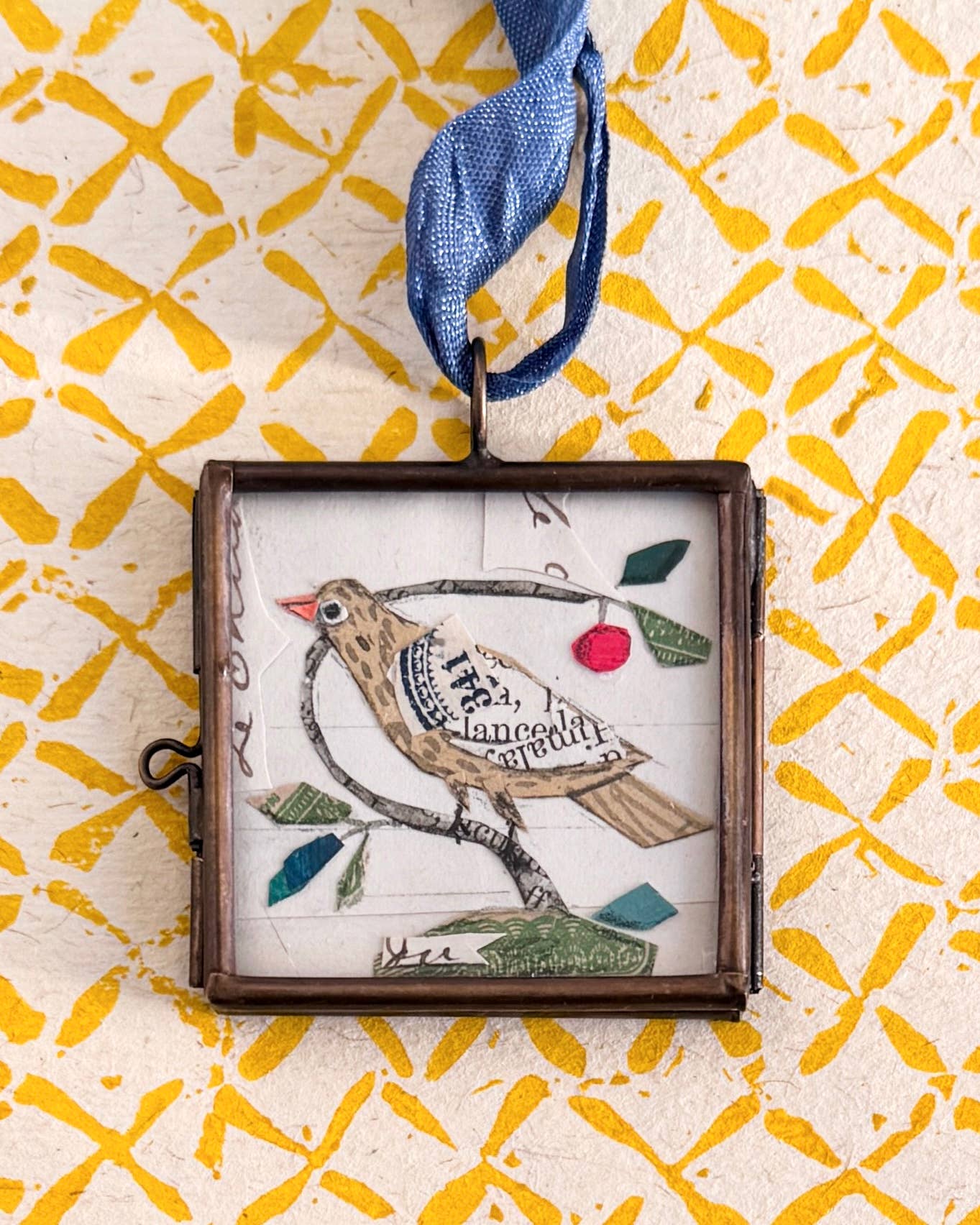 Vintage-style folk bird art locket ornament.