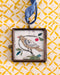 Vintage-style folk bird art locket ornament.