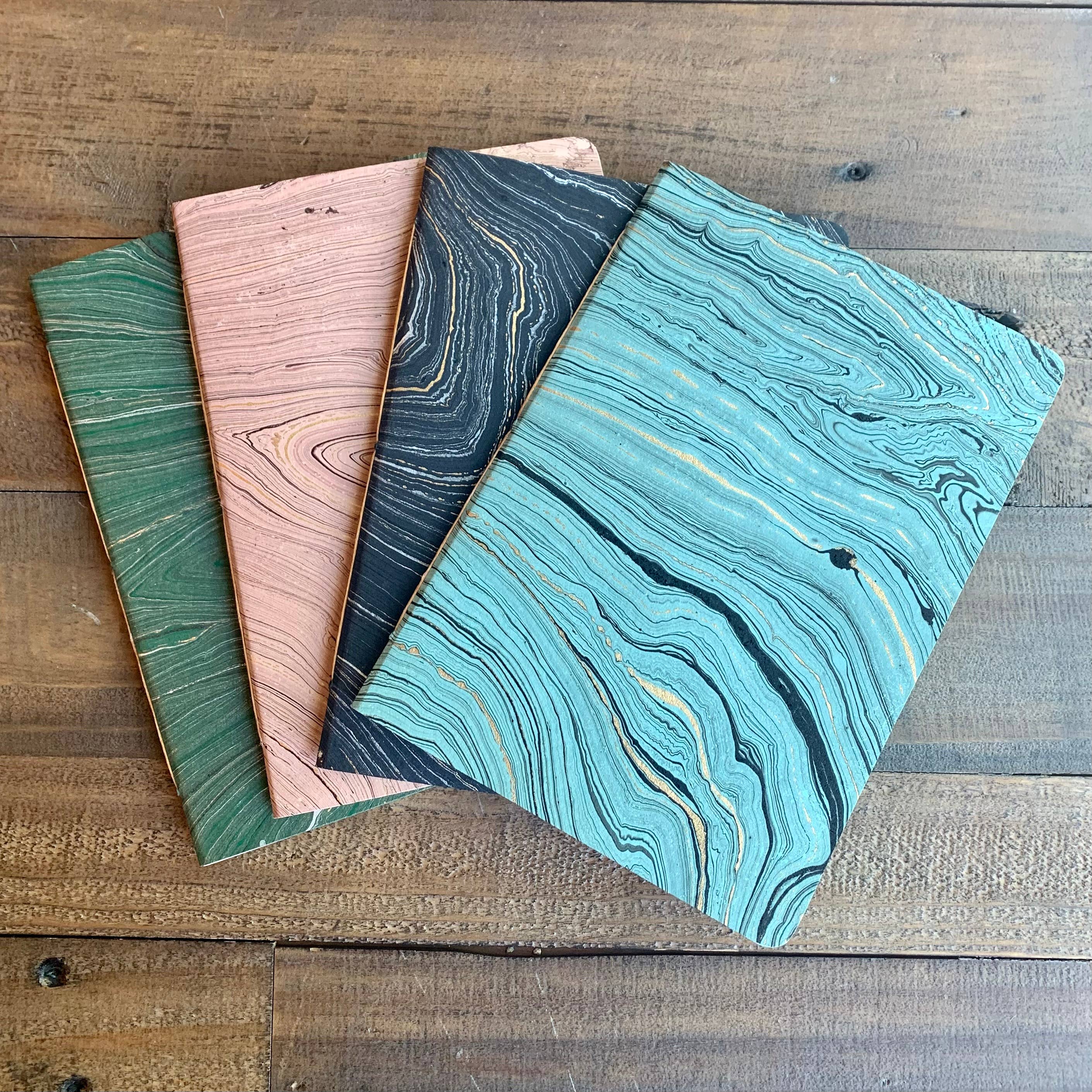 Hand marbled softcover notebook collection by The Casual Bookbinder, showcasing unique marbling patterns on four different notebooks.