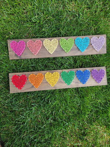 rainbow string hearts on stained wood board