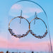 Artistic shot of Everly Herkimer Diamond and Pearl Hoop Earrings by Derive Jewelry against a sunset background, featuring crystal-like diamonds and luminous pearls on a gold hoop.