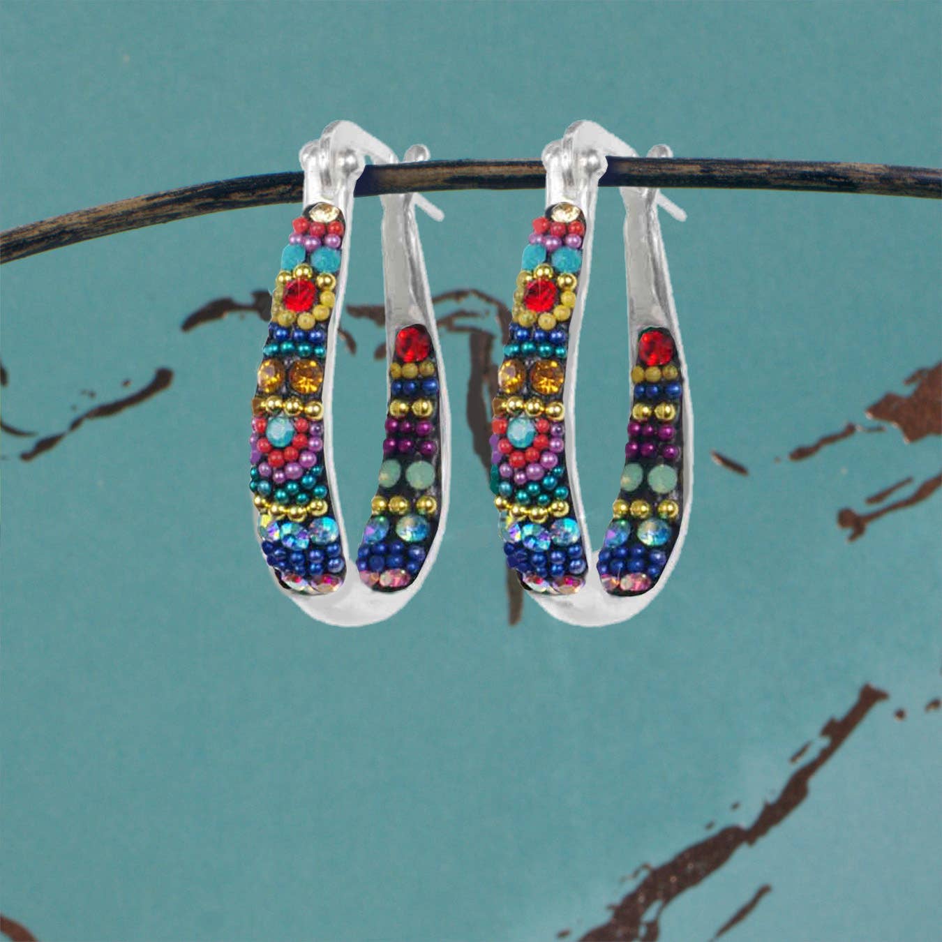 Crystal Small Hoop Earring by Mosaico Jewels showcased against a teal background, adorned with colorful beads and intricate detailing.