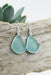 Flat lay of Eco Glass Bezel Drop Silver Earrings: Aqua with a beach-inspired background, emphasizing their coastal elegance.