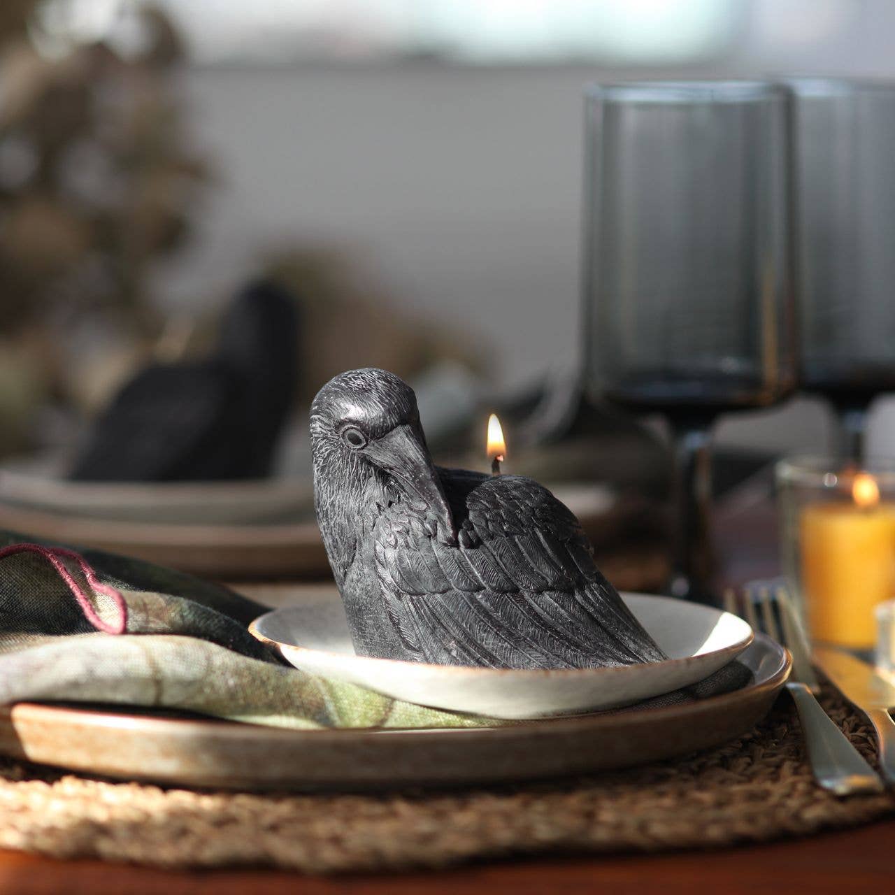 Decorative bird candle on a table setting with plates and cutlery.