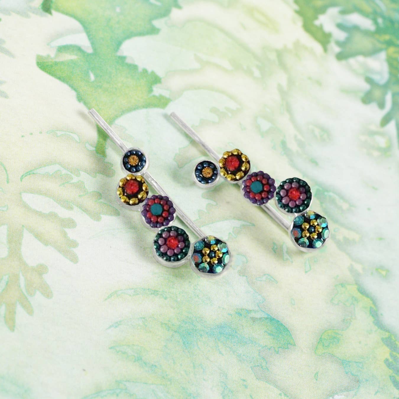 Elegant Falling Circles Earrings by Mosaico Jewels, displayed on a floral background with distinct red and blue sparkling elements.