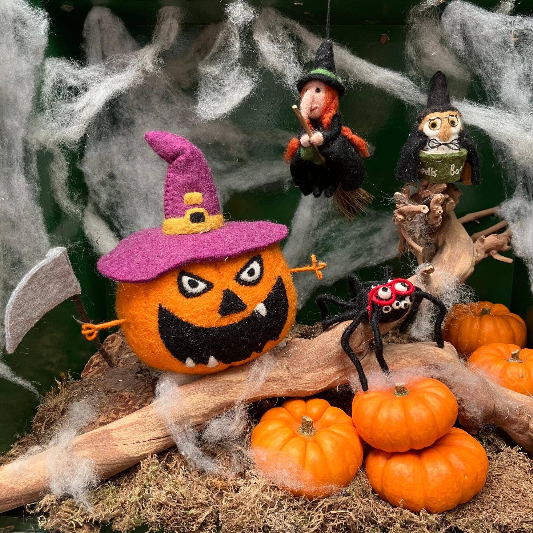 Halloween felt themed ornaments on a branch with cobwebs.