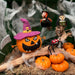 Halloween felt themed ornaments on a branch with cobwebs.