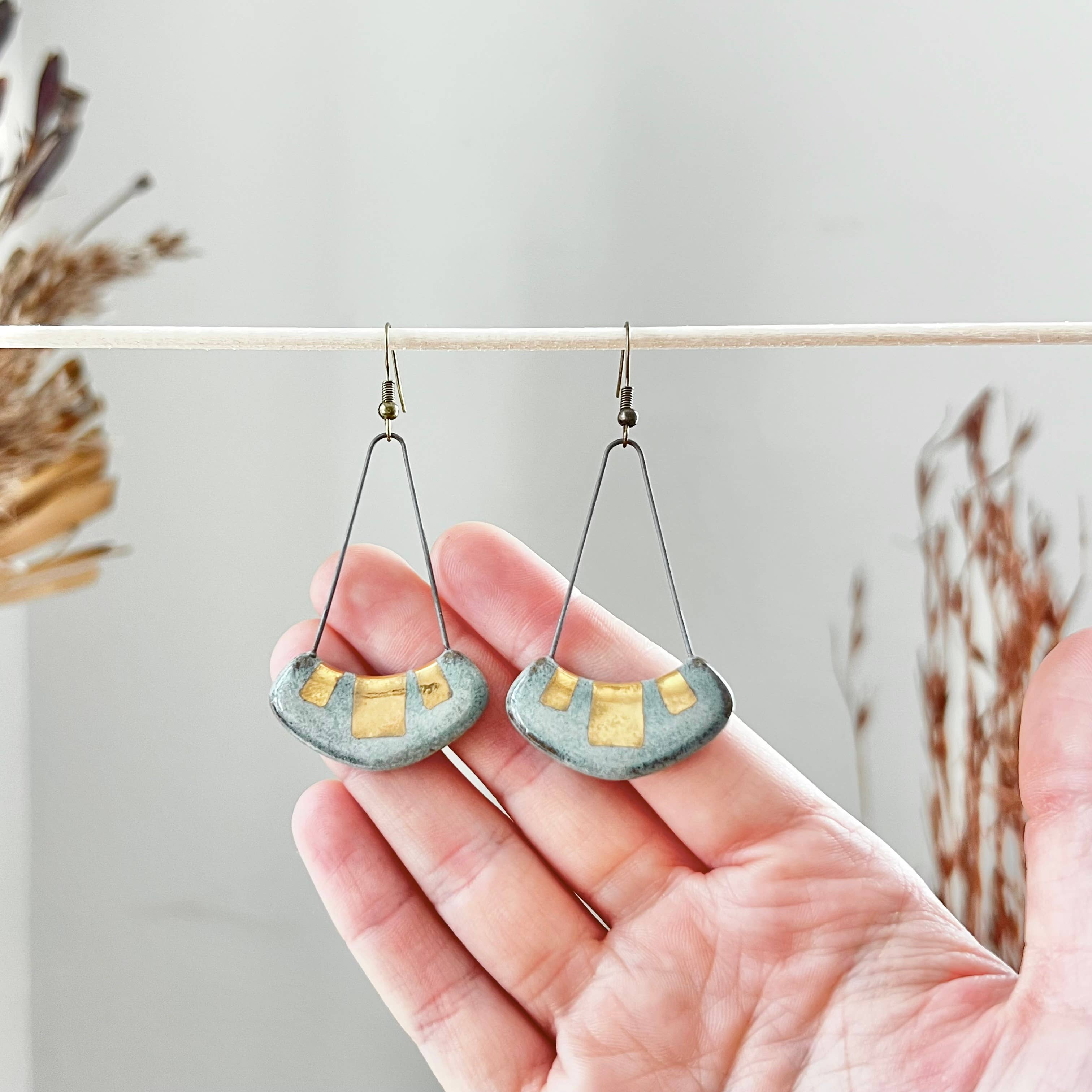 Turquoise and Gold Collar Earrings by The Artifact House, displayed in a hand showing the unique ceramic craftsmanship with turquoise and gold highlights.