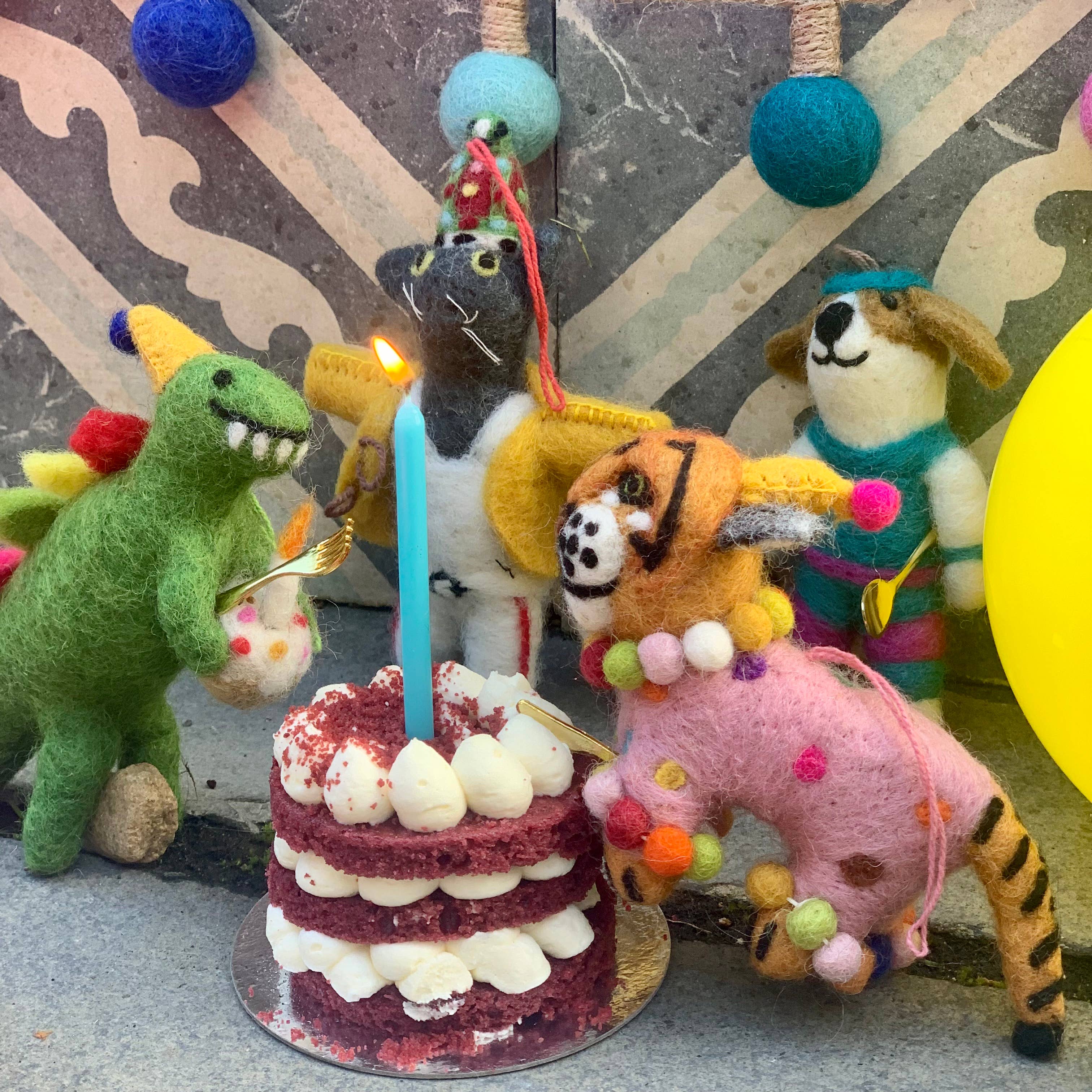 Animal ornaments around a cake with candles on a patterned surface