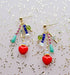 Close-up view of the Heart Charm Earrings by Jill Makes, showcasing the vibrant assortment of beads and the red heart charms, set against a shimmery backdrop.