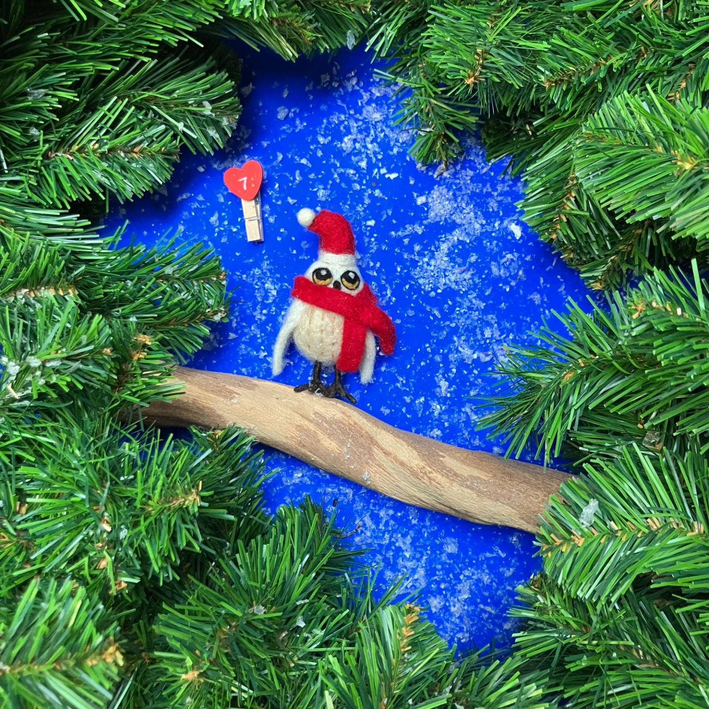 Felt owl ornament in Santa hat on a branch surrounded by Christmas tree