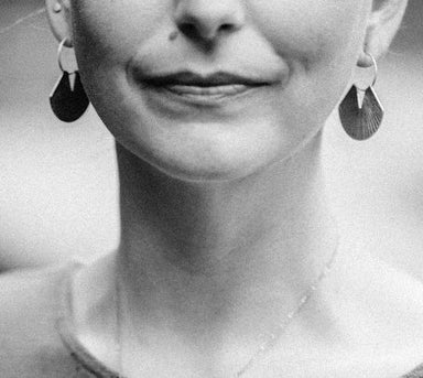 woman wearing brass fan disc earrings