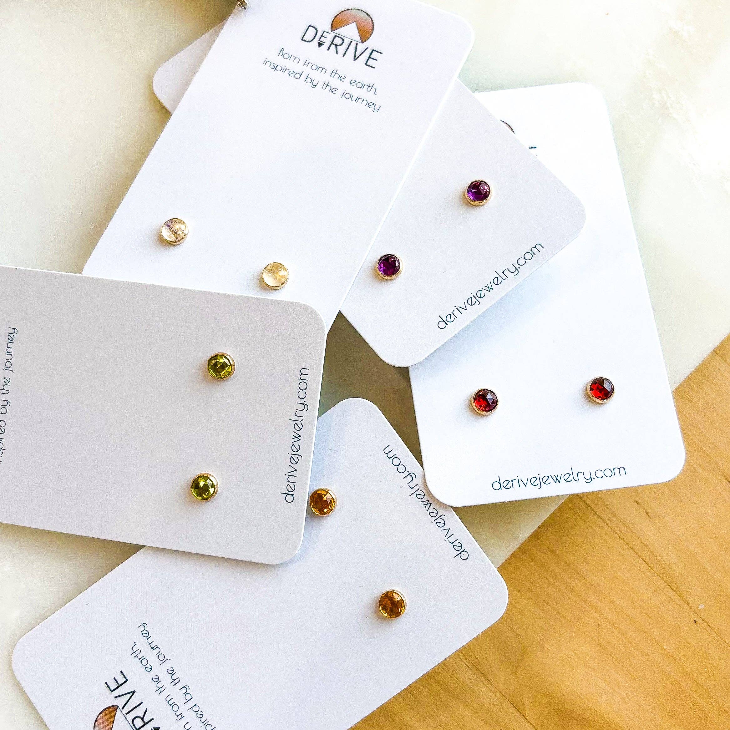 Gemstone Stud Earrings from Derive Jewelry displayed on cards, showcasing a variety of gemstones including Amethyst and Peridot, perfect for gifting.