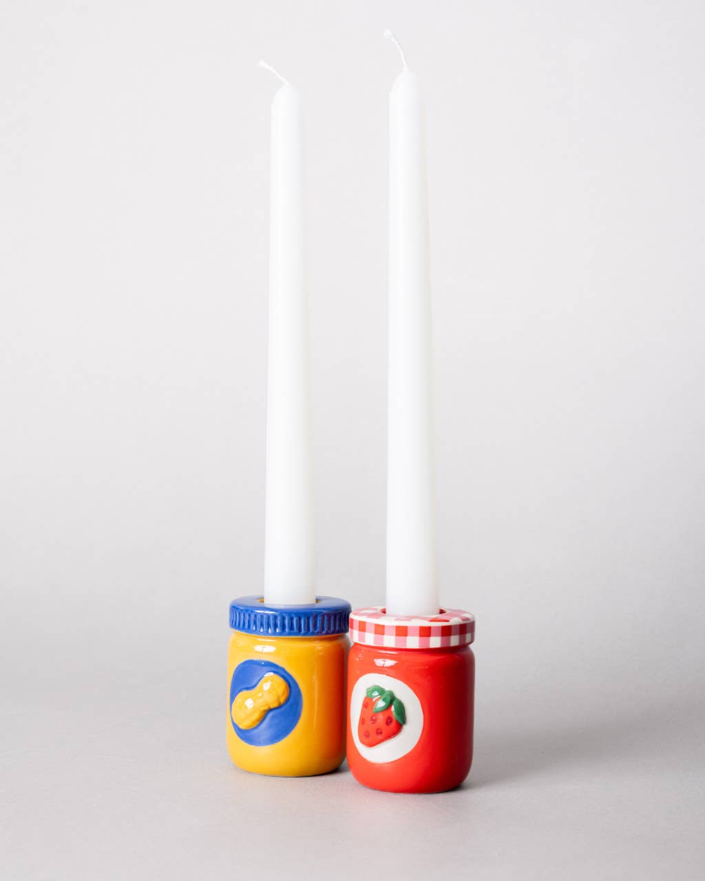 Two colorful jar-shaped candle holders with candles inside 