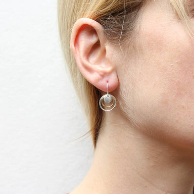 Close-up of Mini Disc and Layered Rings Wire Earrings by Marjorie Baer worn on an ear, highlighting the elegant craftsmanship and layered composition.
