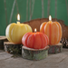Three pumpkin-shaped candles on wooden bases 