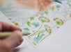 Detail shot of a bluebird print by Emily Uchytil, featuring the artist's signature and vibrant floral elements, perfect for collectors and nature lovers.