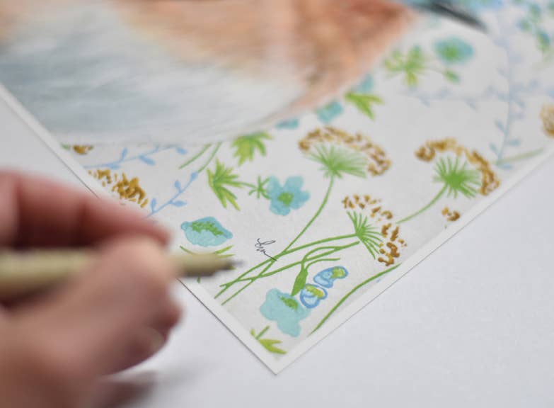 Detail shot of a bluebird print by Emily Uchytil, featuring the artist's signature and vibrant floral elements, perfect for collectors and nature lovers.
