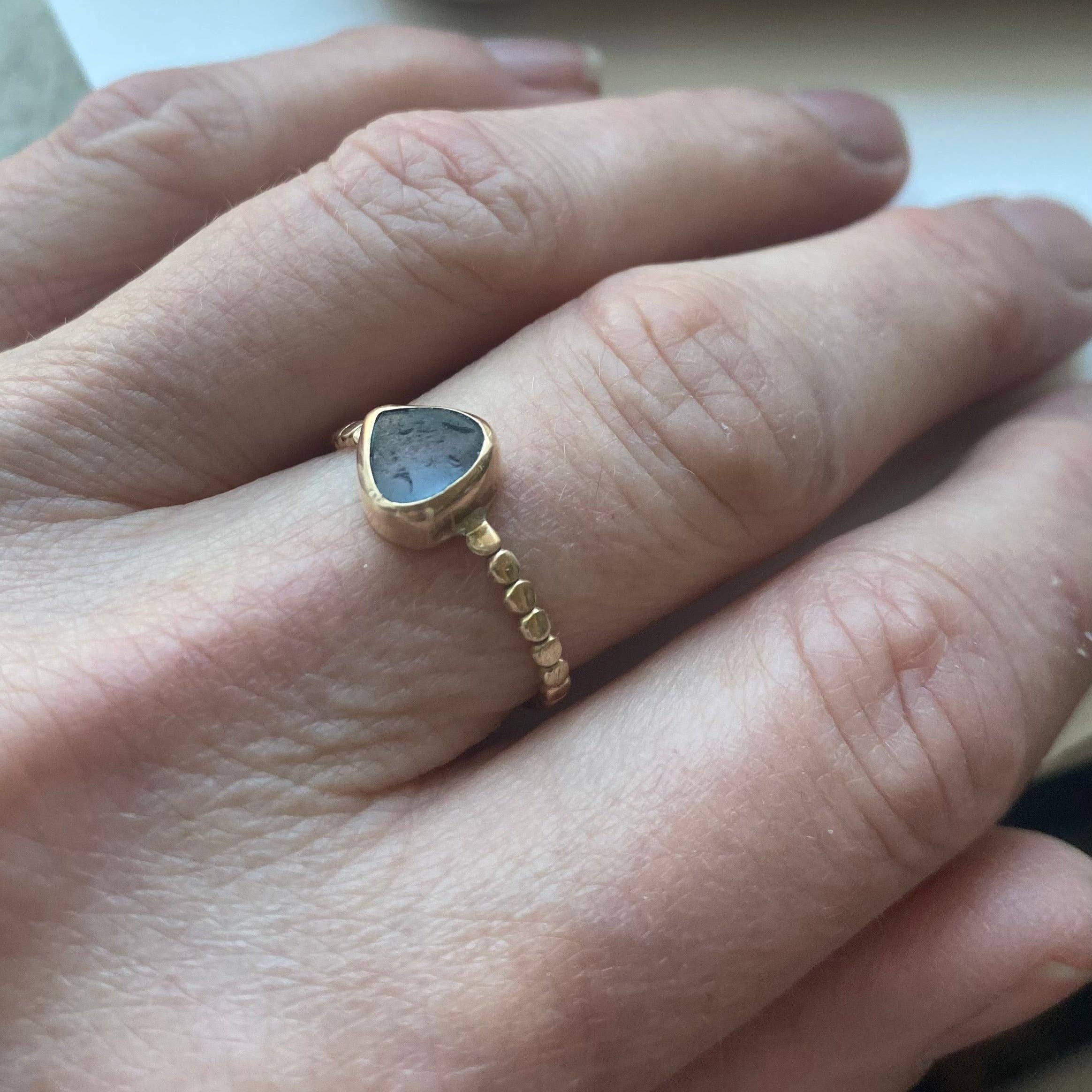 The Repetition Band | Sea Glass Ring by Kate Samson Design worn on a hand, highlighting its handmade 14k gold beaded band and distinctive sea glass.