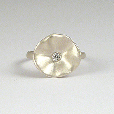 Silver ring with a round, textured design and a small diamond