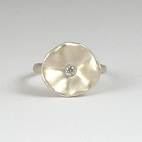 Silver ring with a round, textured design and a small diamond