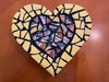 Handcrafted heart-shaped mosaic by Hearts for the Arts | Carino, featuring vibrant ceramic tiles and Italian pottery on a wooden base, showcasing intricate designs.