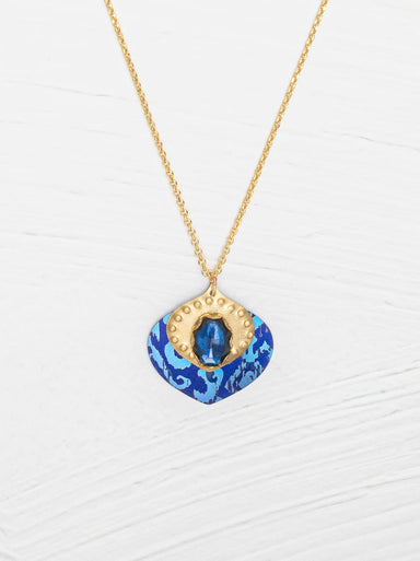 Arabella Pendant Necklace featuring a vibrant glass stone and textured gold on a glowing niobium backdrop.