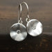 Pair of silver earrings with round designs and small diamonds 